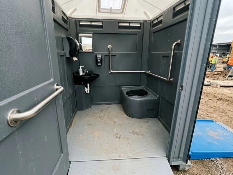 Interior of ADA portable toilet showing 60-inch clearance and grab bars